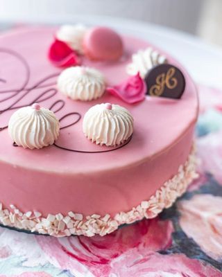 Różowy tort firmowy z bezami i czekoladowym monogramem